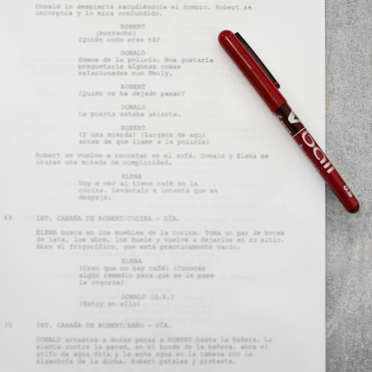 Guion manuscrito en papel blanco con notas en color rojo.