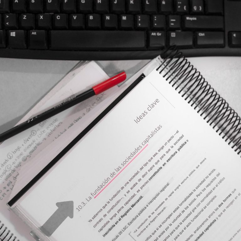 Documento con texto resaltado y rotulador rojo sobre una mesa con teclado.