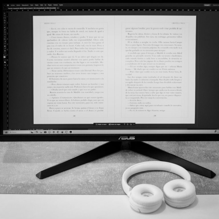 Pantalla de ordenador mostrando texto impreso, con auriculares blancos en la mesa.